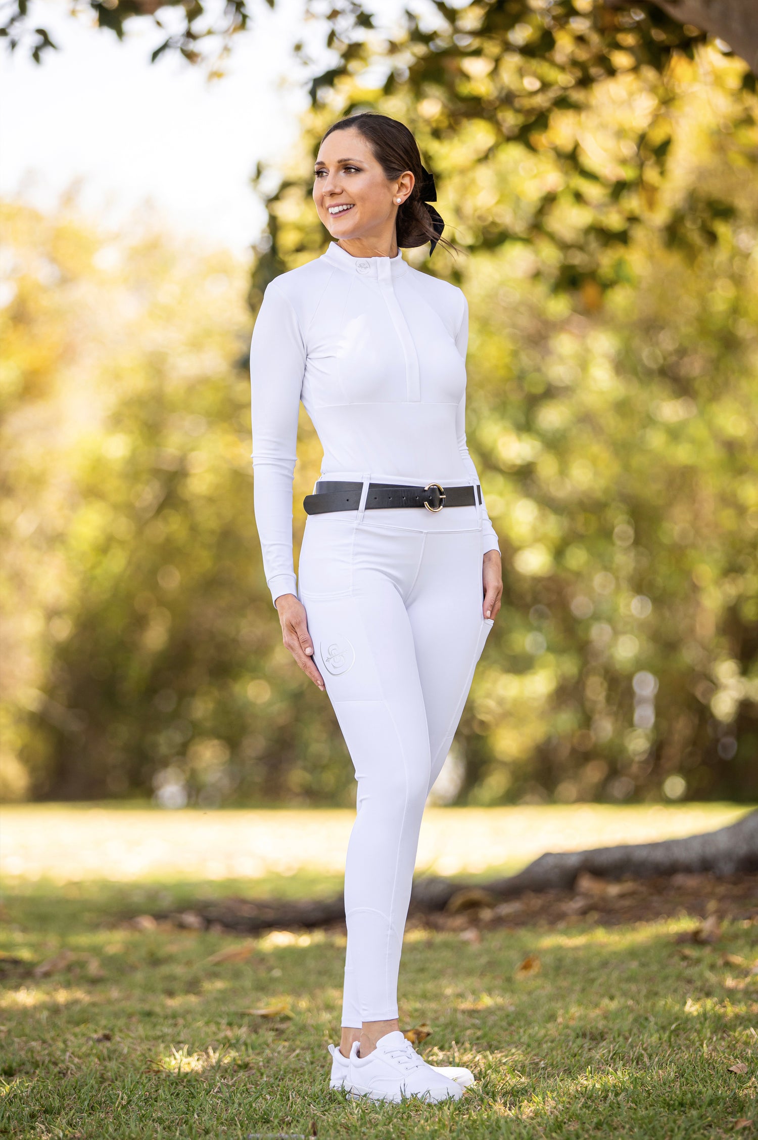 An image of a girl dressed in the Sabi Equestrian Long Sleeve Paradigm Design Base Layer and Sculpt Performance Hybrid Breeches in Winter White